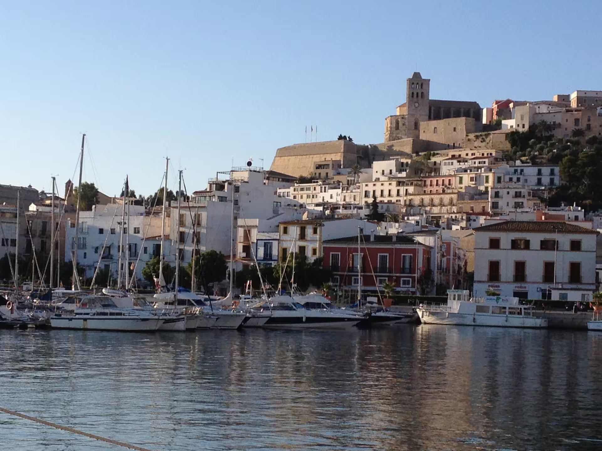 Ibiza Port marina with sailboats and Dalt Vila skyline at sunset, stop on Ibiza Night hotel transfer with free time