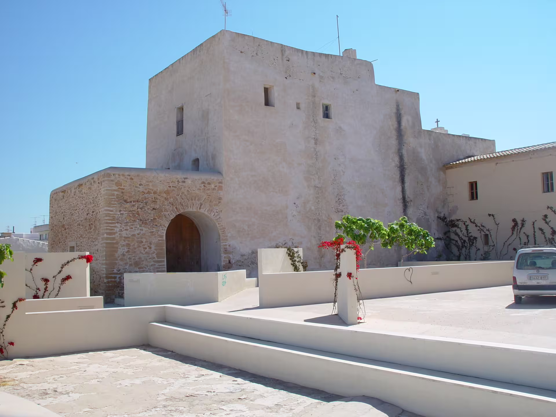 Whitewashed Ibiza church fortress in a sunny plaza, stop on Ibiza bus tour with official guide and ferry
