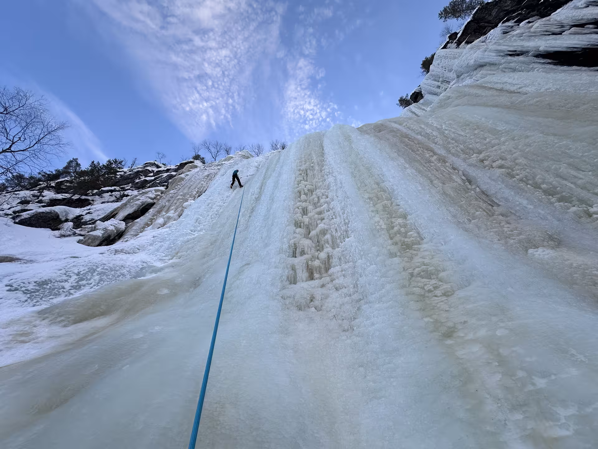 Climber tackling a massive ice formation in Rovaniemi, Finland, under a clear blue sky, ideal for adventure seekers.