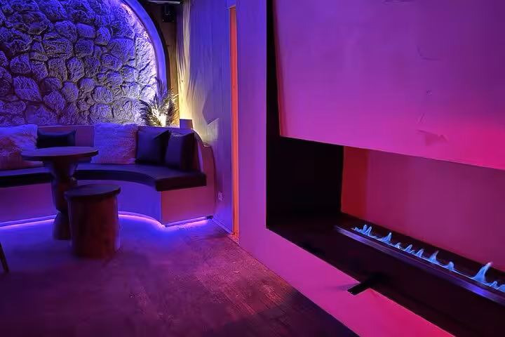 Ambient IceBar Cologne lounge area featuring neon lighting, plush seating, and a contemporary fireplace for relaxation.