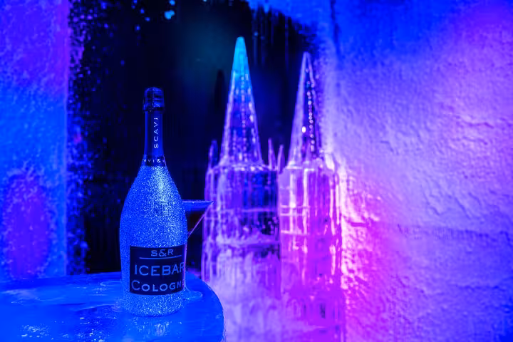 Chilled bottle of IceBar Cologne sparkling wine on an ice table with illuminated ice sculptures in the background.
