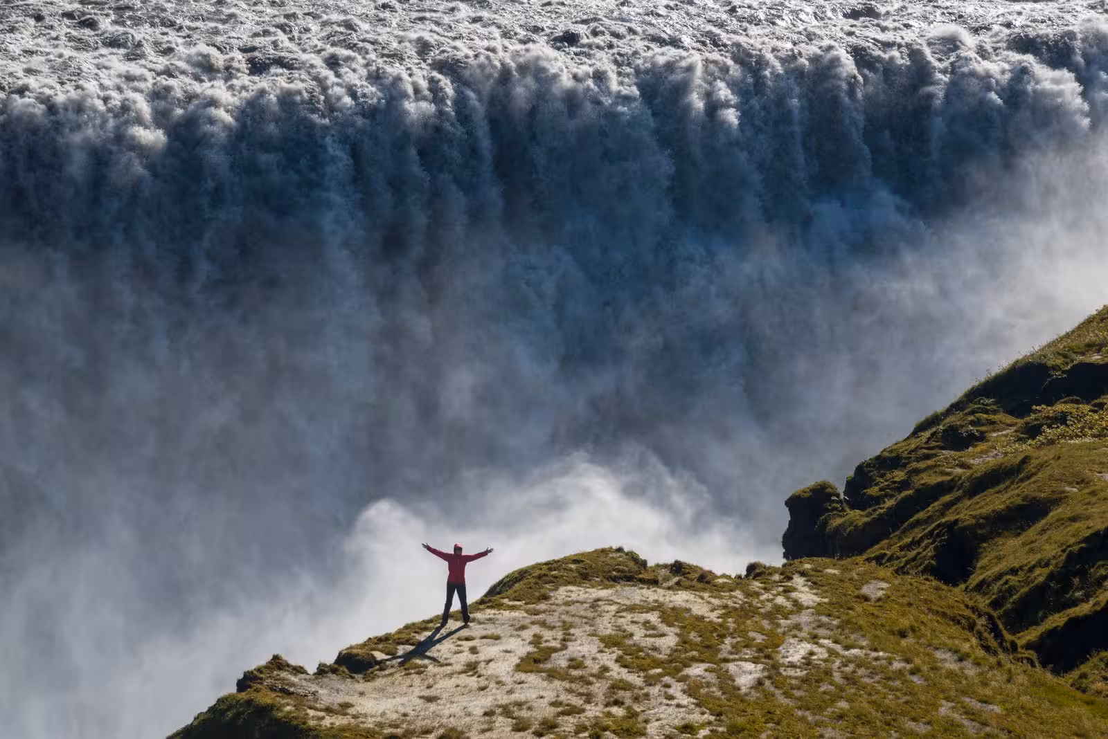 Majestic Dettifoss waterfall with a lone hiker enjoying the breathtaking view, perfect for Iceland explorers.