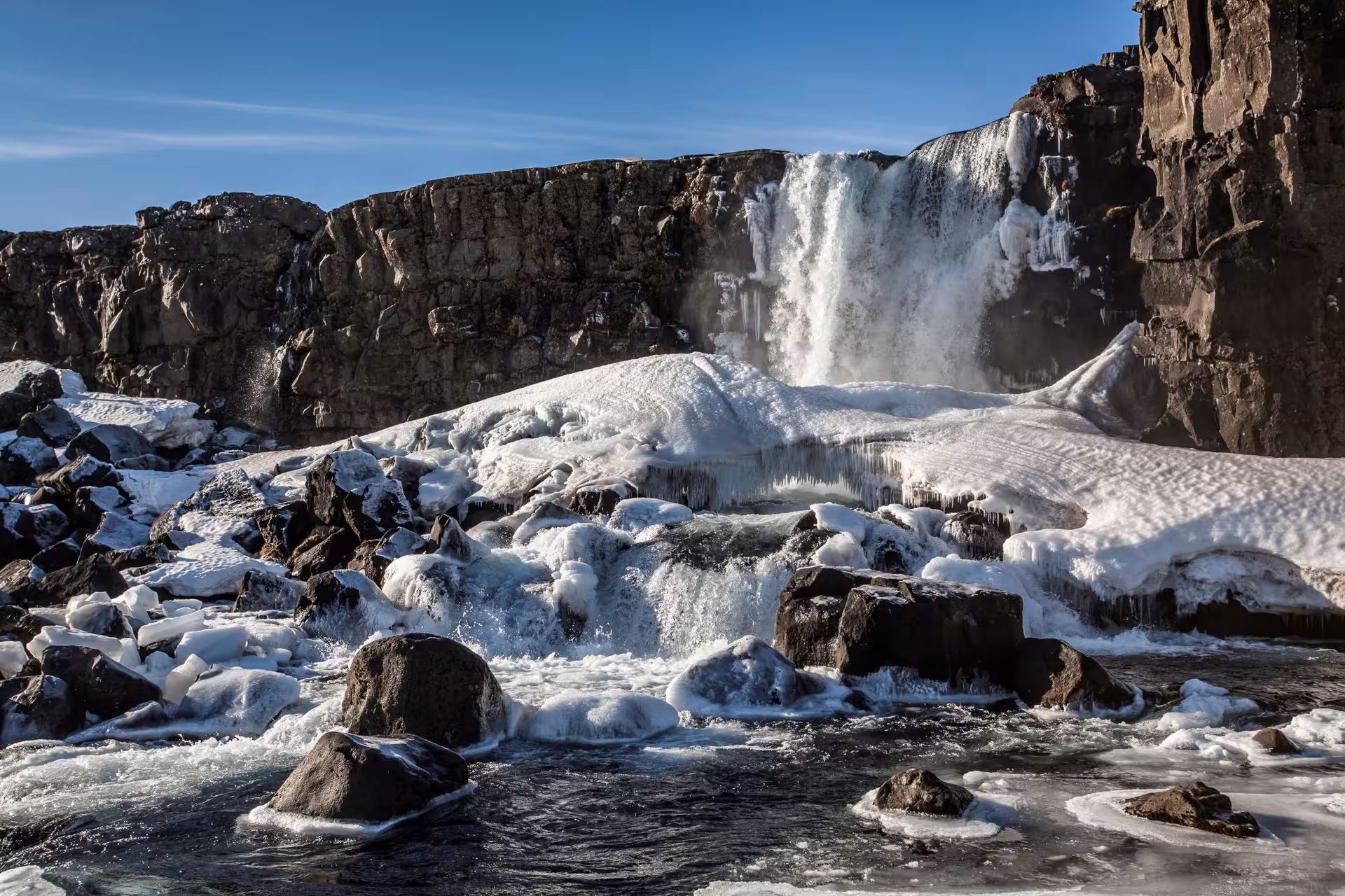 Frozen Öxarárfoss waterfall surrounded by icy rocks, showcasing Iceland's winter beauty on a 6-day stopover tour.