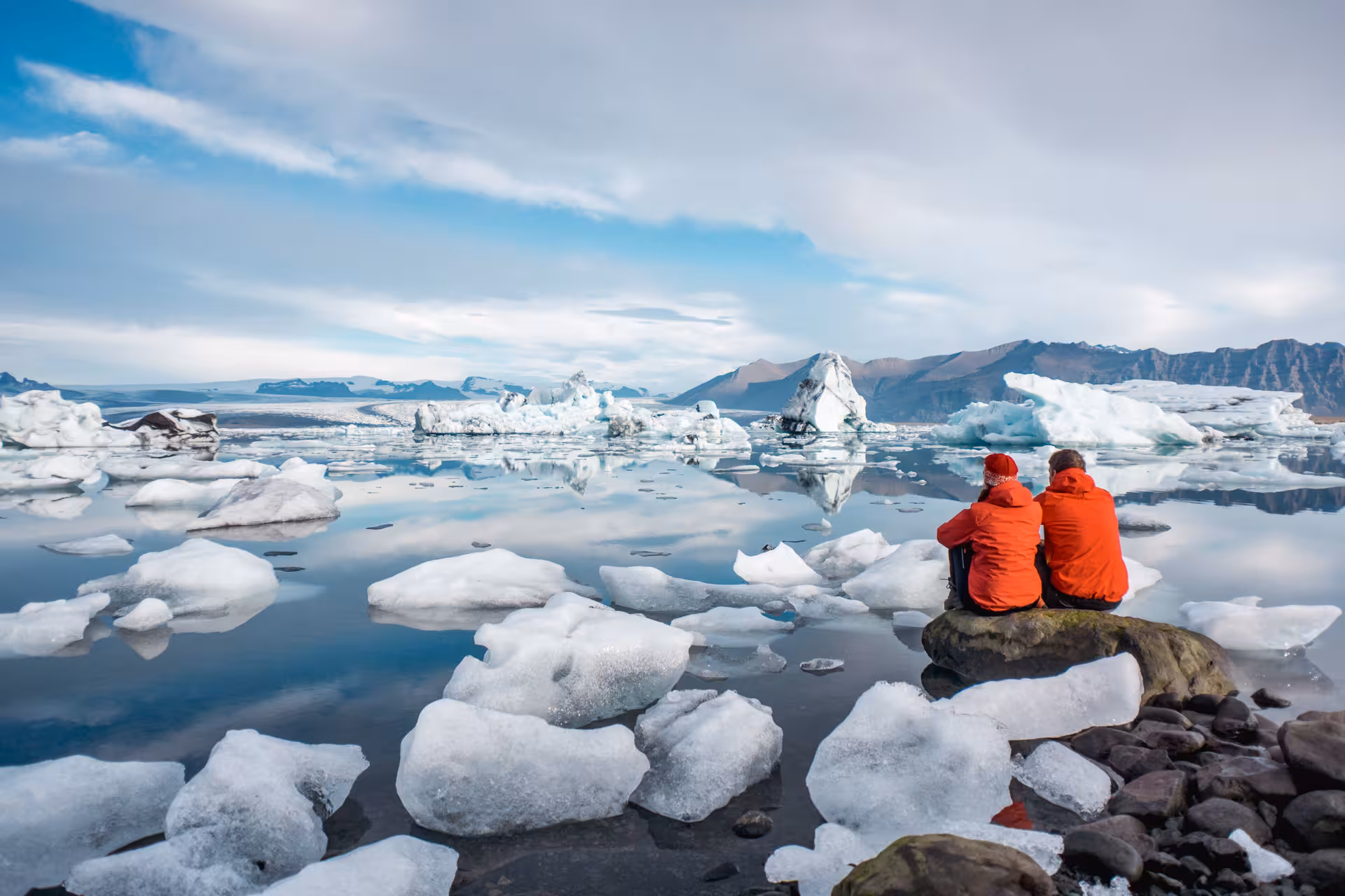 Travelers in red jackets admire Jökulsárlón glacier lagoon icebergs, highlight of a 7-day small group Iceland tour
