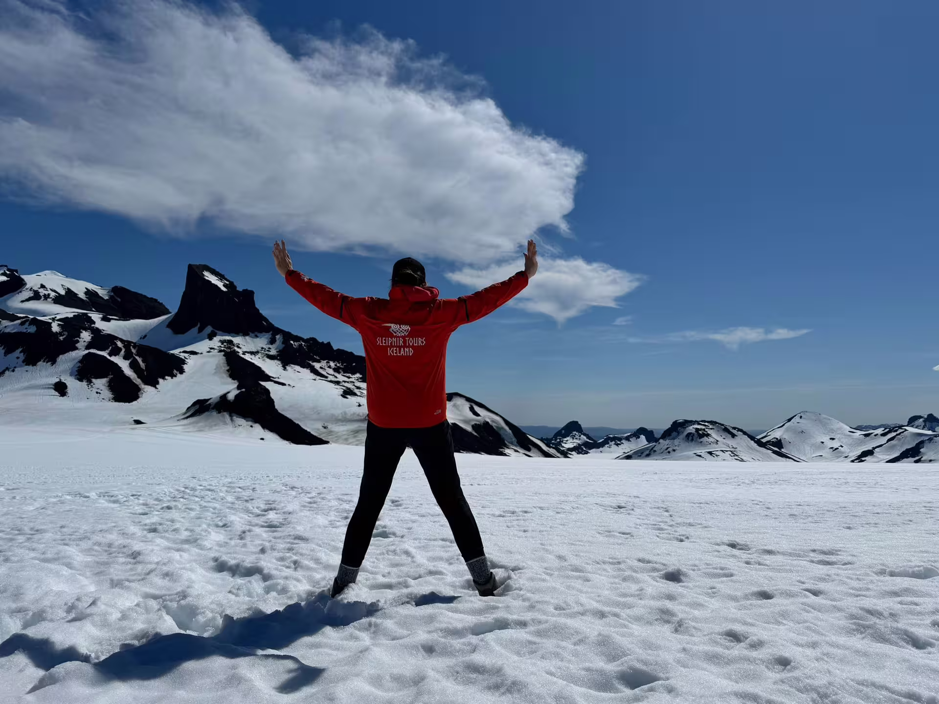 Traveler on a snowfield with volcanic peaks on an Iceland glacier, part of Golden Circle and monster truck tour
