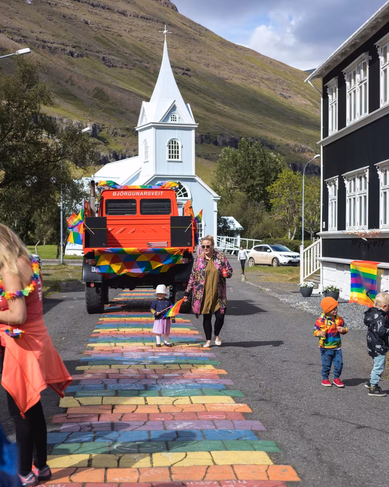 Colorful street scene with rainbow walkway and white church in Seyðisfjörður, Iceland Grand Tour adventure.