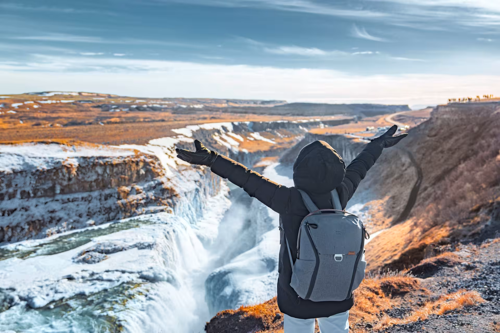 Traveler embracing the stunning view of Iceland's majestic Gullfoss waterfall during a 4-day stopover tour.