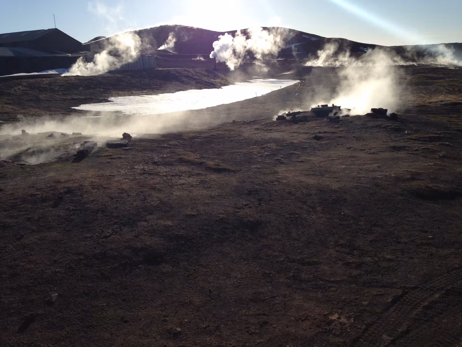 Geothermal steam vents releasing vapor over a rugged landscape near Lake Myvatn, showcasing Iceland's natural wonders.
