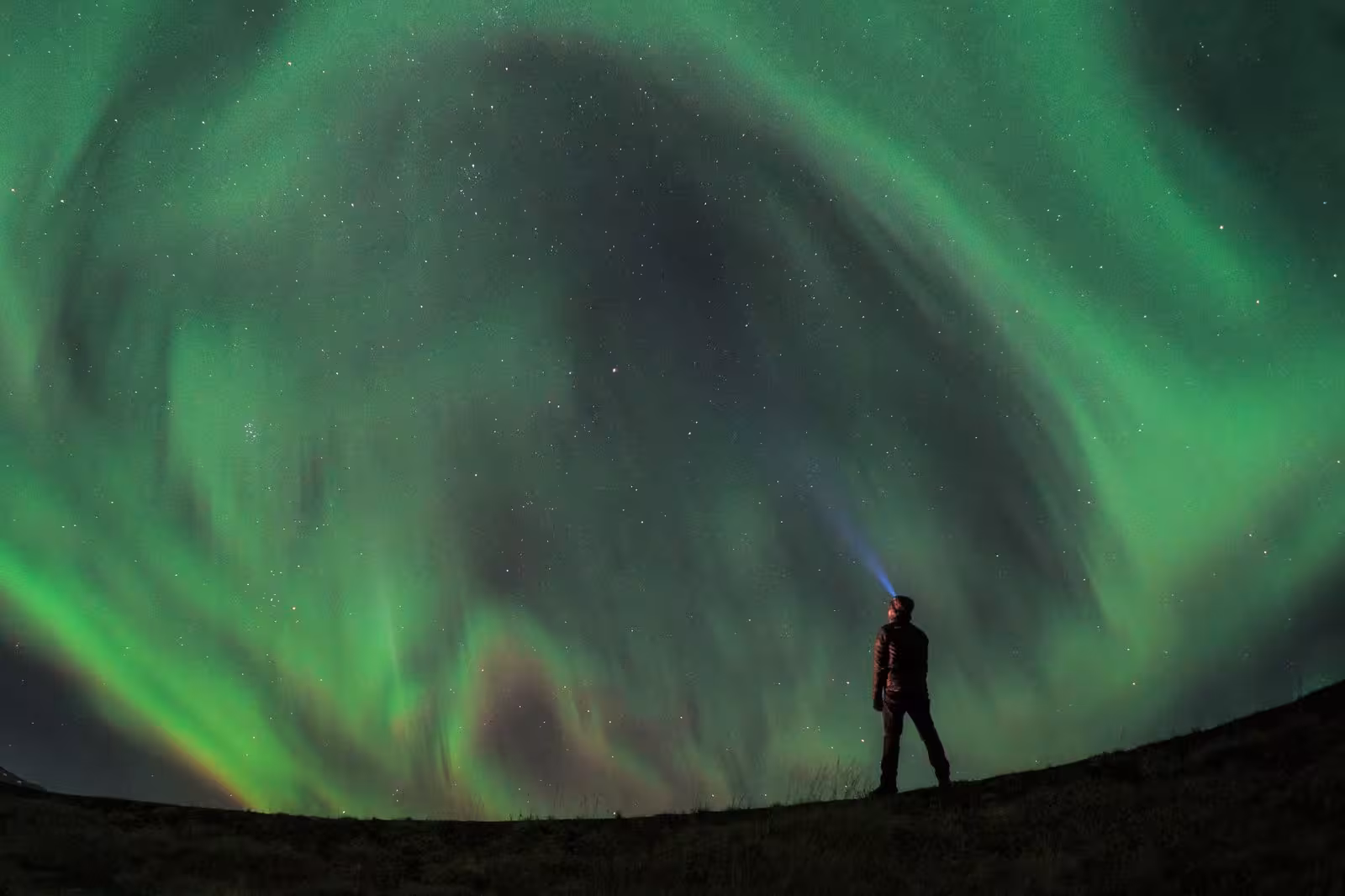 Person gazing at the stunning Northern Lights in Iceland, ideal for a 5-day stopover experience.