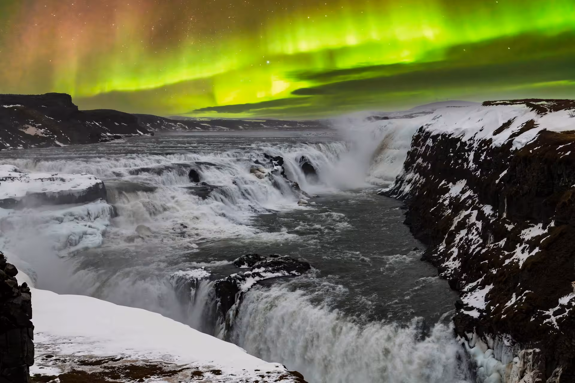 Northern lights illuminating Gullfoss waterfall with vibrant green hues on the Iceland tour.