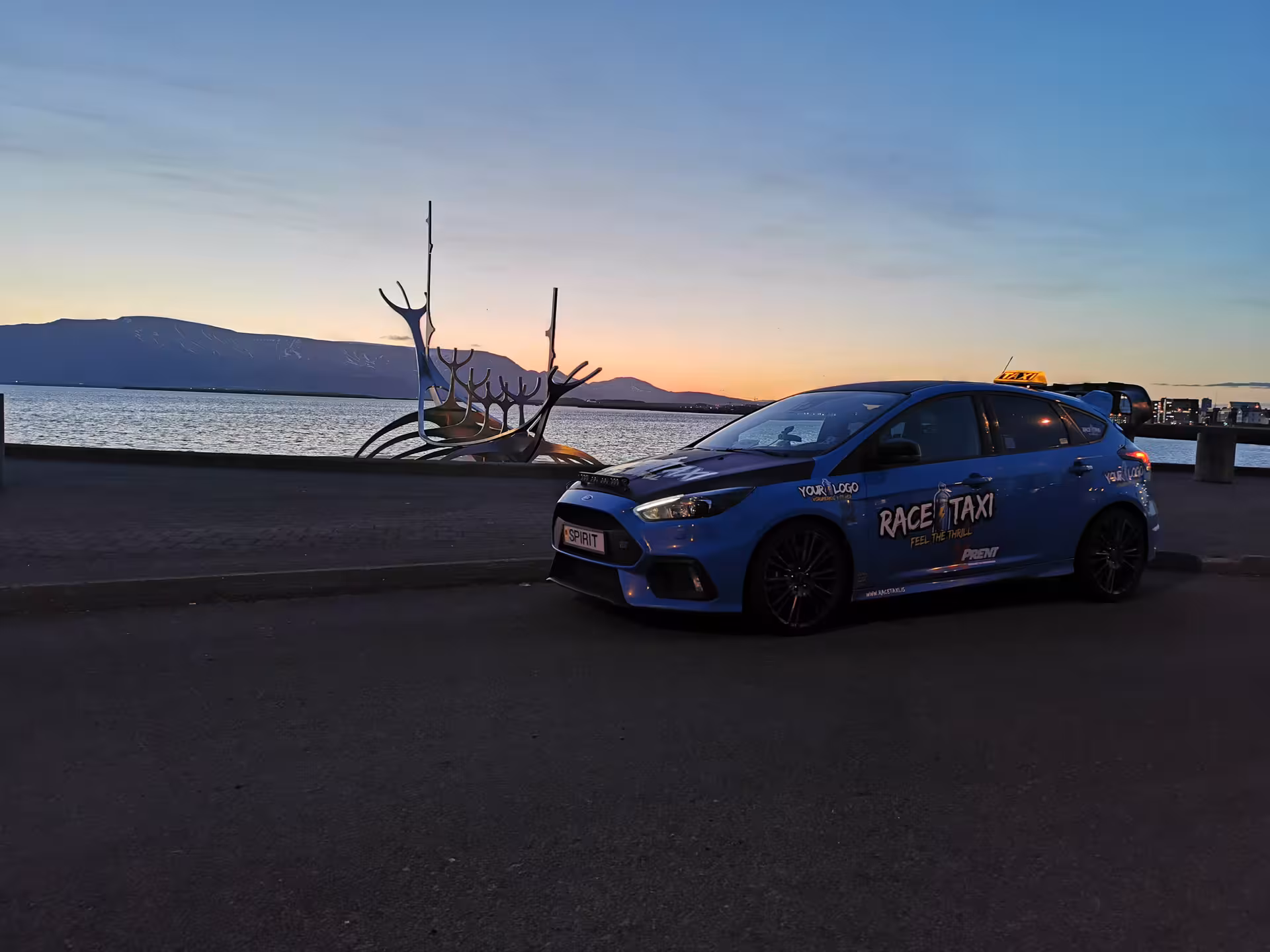 Blue rally car taxi by Reykjavik Sun Voyager at sunset, private airport transfer from Keflavik to city