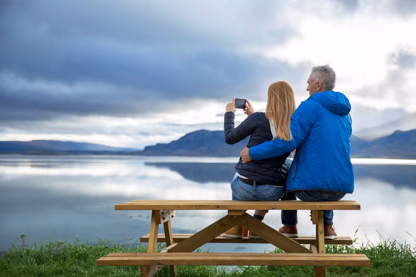 Couple taking a selfie by a serene Icelandic lake, capturing the tranquil beauty of West Iceland's landscape.