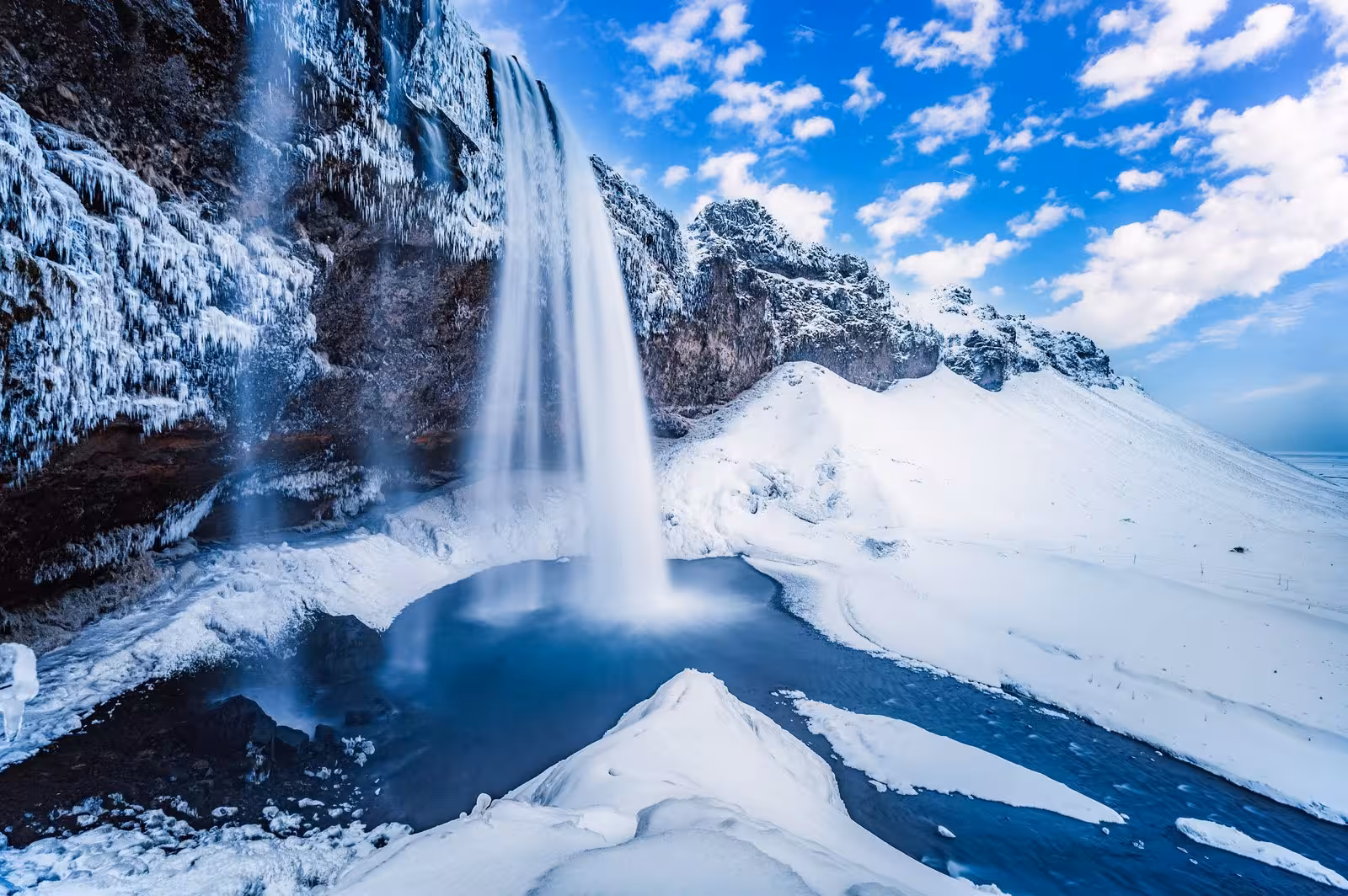 Stunning winter scene at Seljalandsfoss waterfall, Iceland, showcasing icy cliffs and pristine snow-covered landscape.