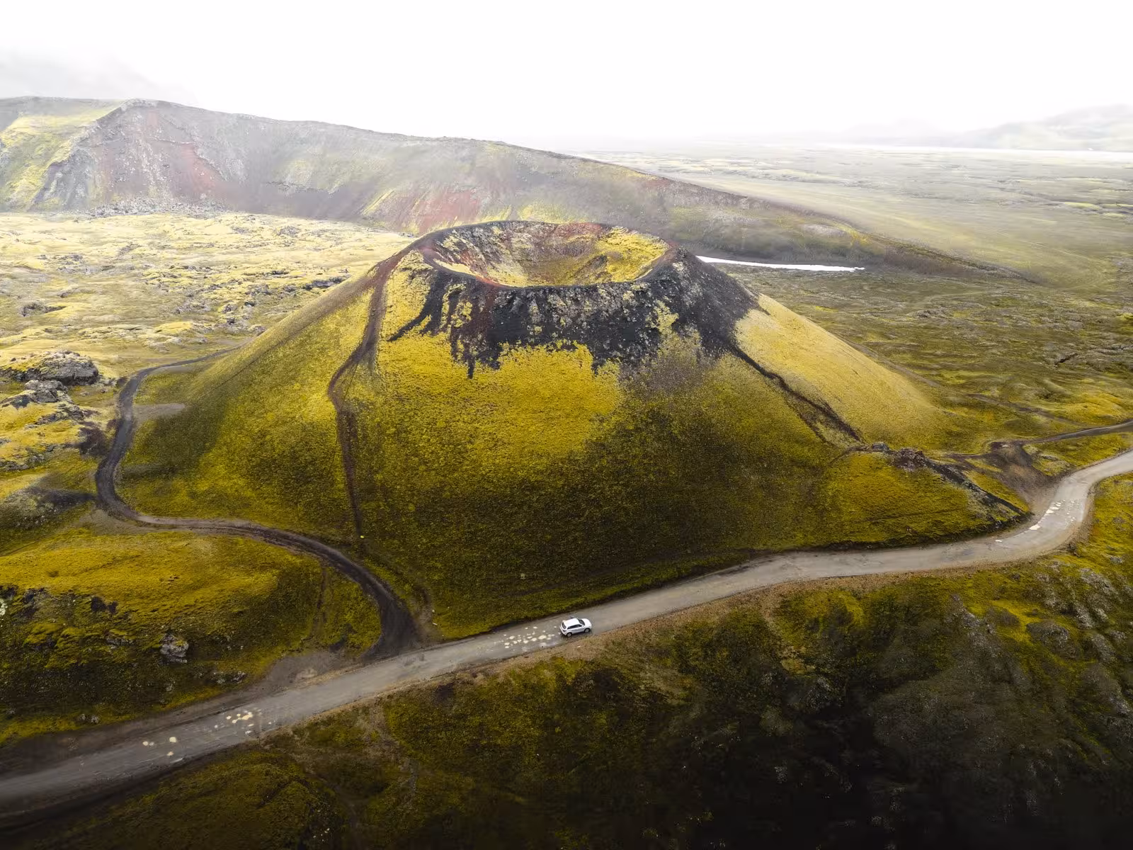 Aerial view of a volcanic crater surrounded by mossy terrain, highlighting Iceland's unique geological features.