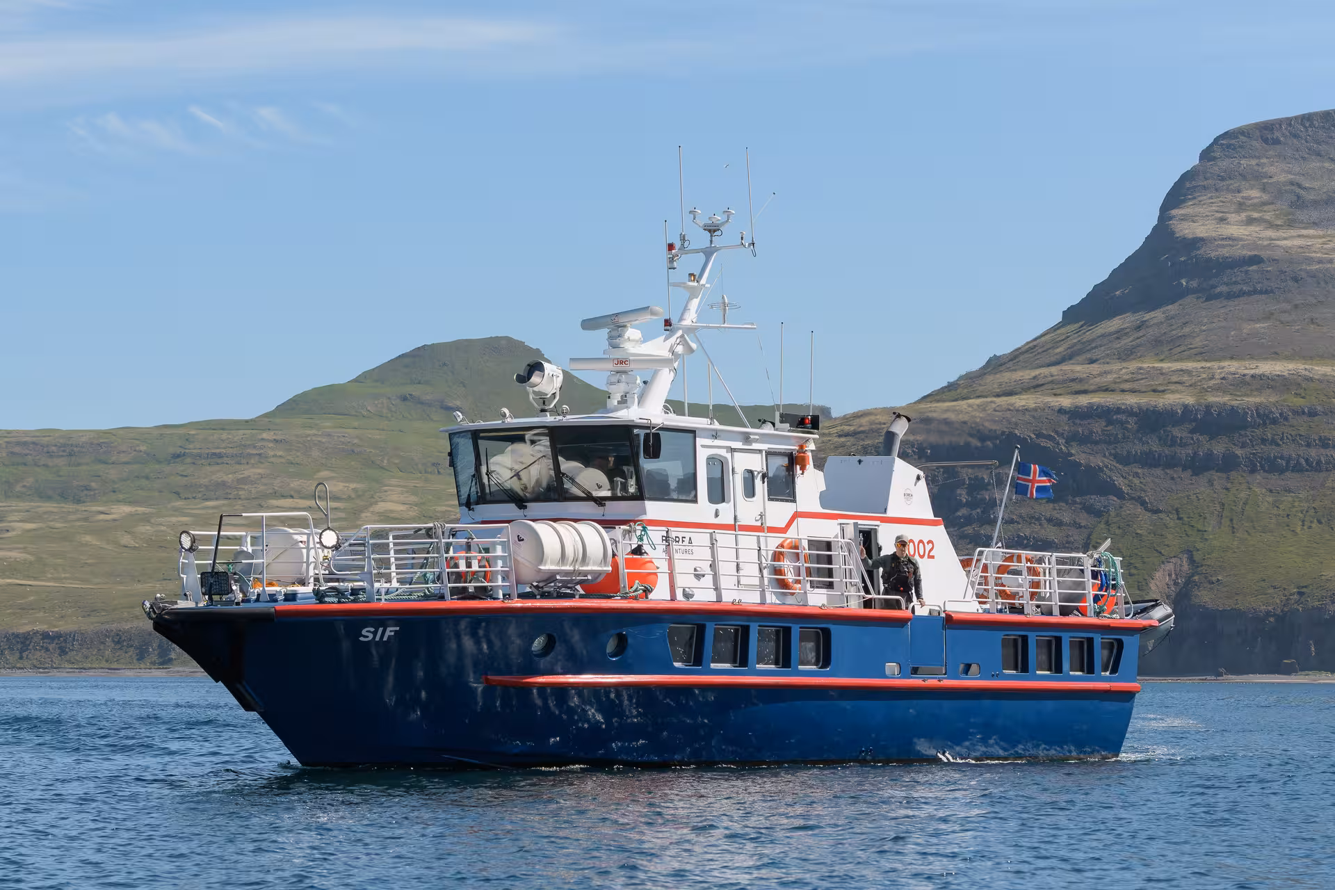 Iceland whale watching boat cruising coastal fjord, ideal base for solar eclipse viewing at sea