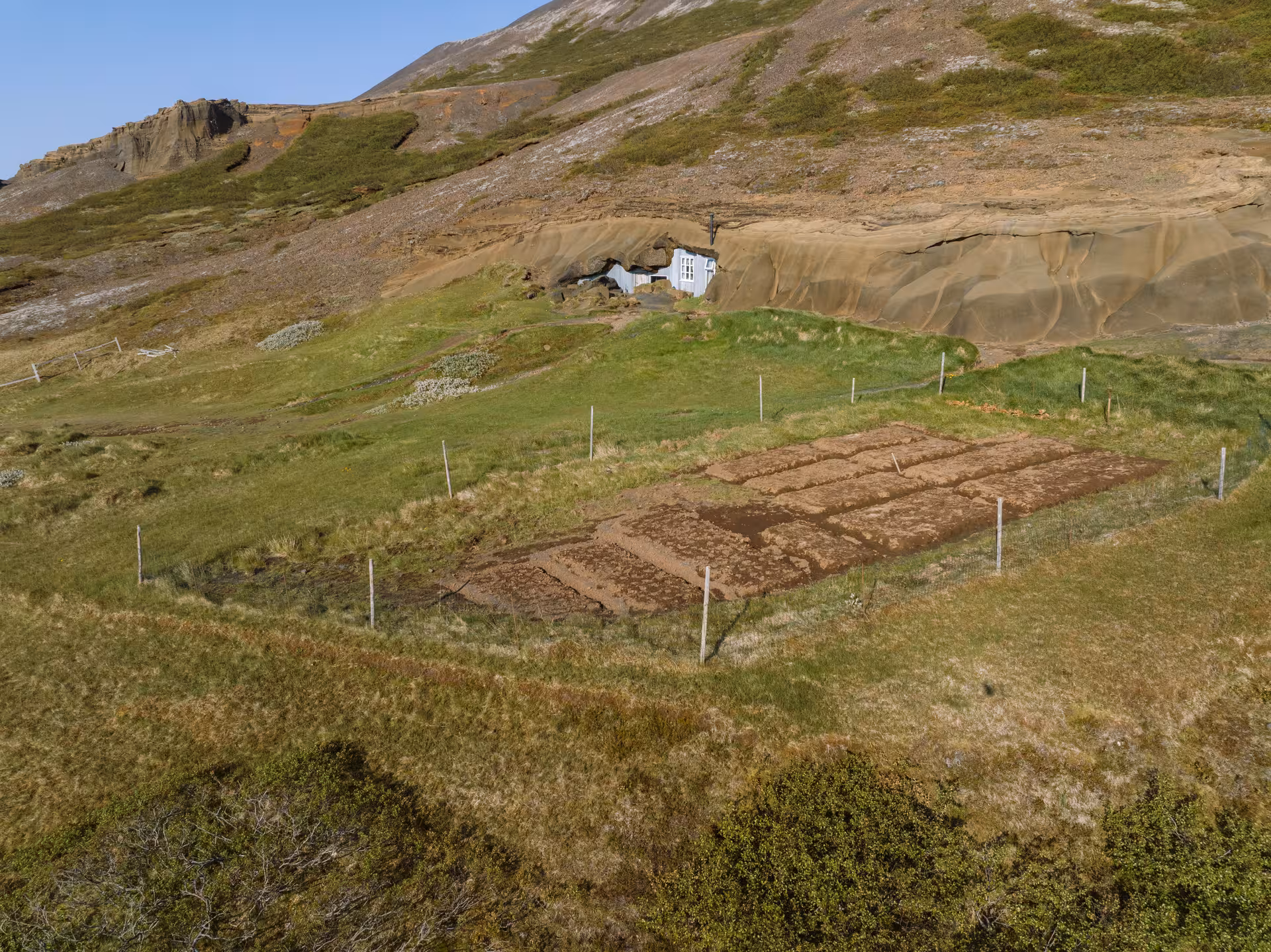 Scenic view of Icelandic cave house entrance in lush green landscape ideal for private tours and food tasting.