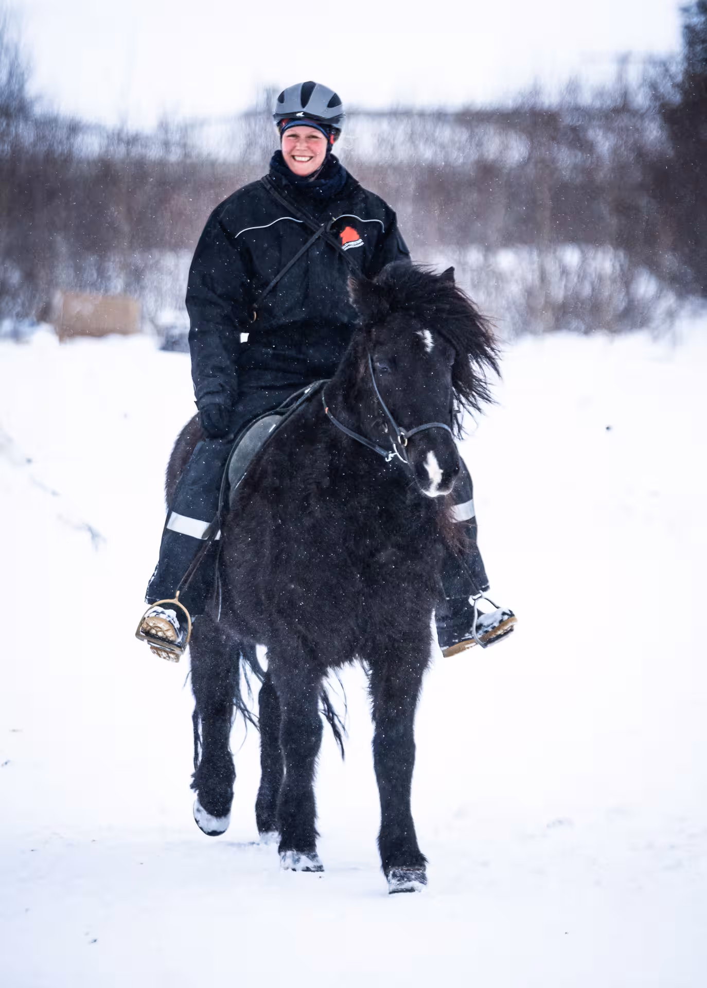 Smiling rider on Icelandic horse in snowfall, winter horseback adventure on 02D Midwinter Warmth tour