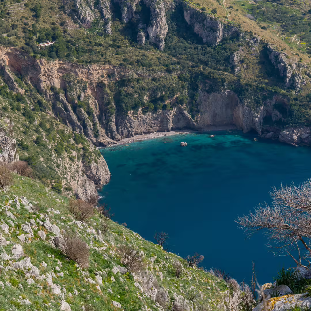 Scenic Ieranto Bay from hiking trail, with turquoise water, rocky cliffs and Mediterranean scrub near Punta Campanella
