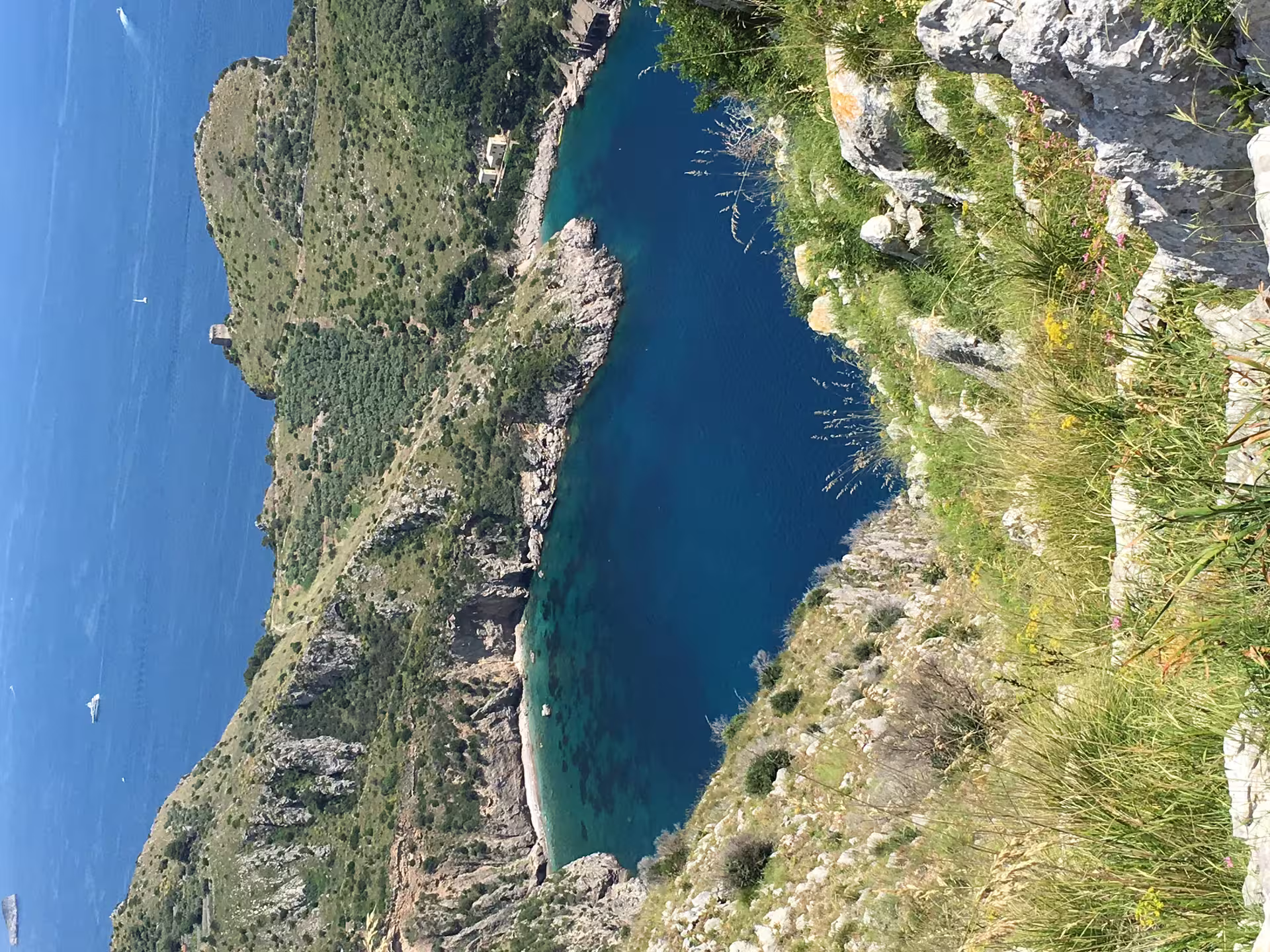 Panoramic view of Ieranto Bay’s turquoise water and rugged cliffs seen from the trekking trail to Punta Campanella