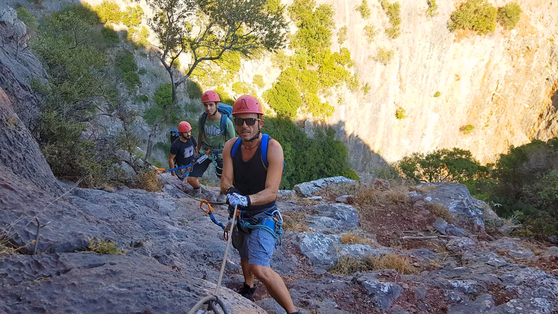Adventurers abseiling down the rugged cliffs of Gutturu Xeu canyon in Iglesias, showcasing thrill and natural beauty.