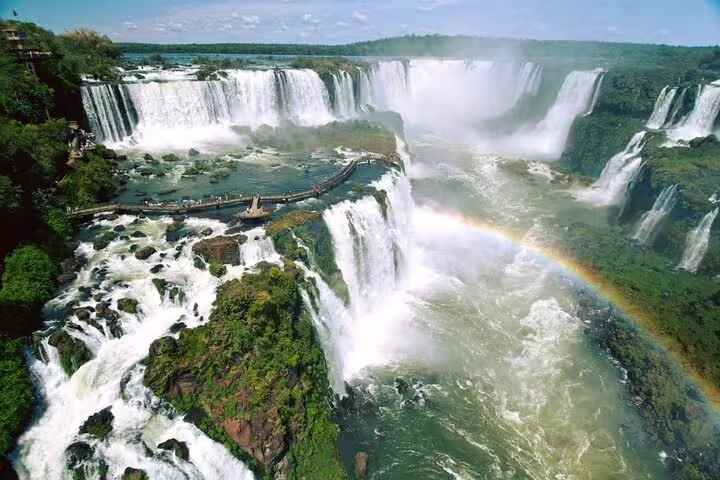 Aerial view of Iguazu Falls with a vibrant rainbow and lush greenery, perfect for a 4-day guided tour experience.
