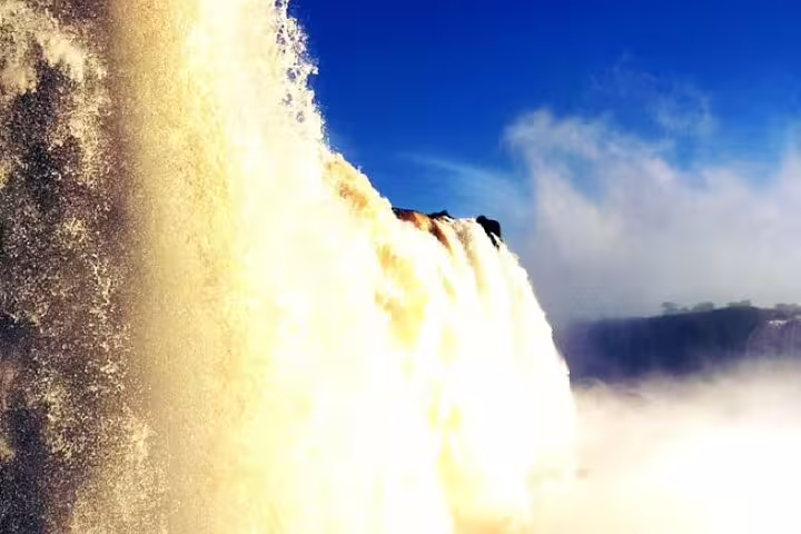 Majestic Iguazu Falls cascading under a clear blue sky, offering a breathtaking view for nature enthusiasts.