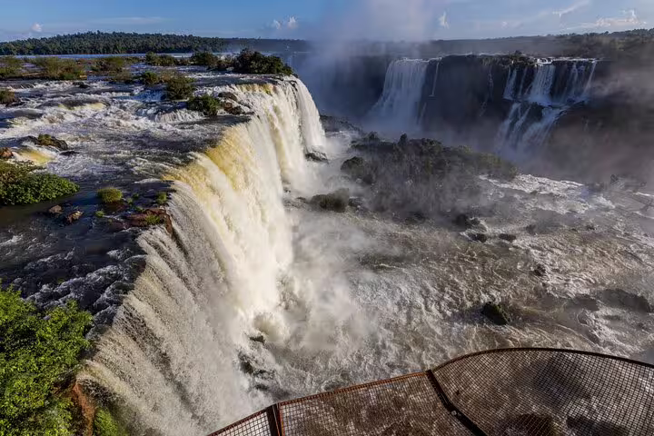 Panoramic vista of Iguazu Falls with mist rising, showcasing the natural wonder's powerful and awe-inspiring beauty.