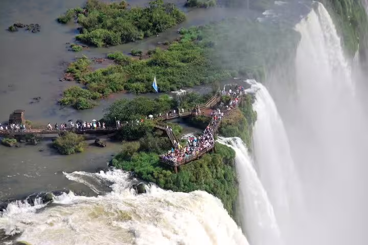 Visitors on a boardwalk enjoy stunning close-up views of Iguazu Falls cascading into lush greenery on a private tour.