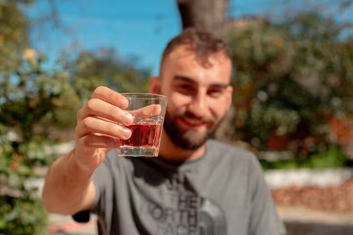 Young man toasting with a glass of local red wine during a sunny Ikaria family-run winery tasting experience