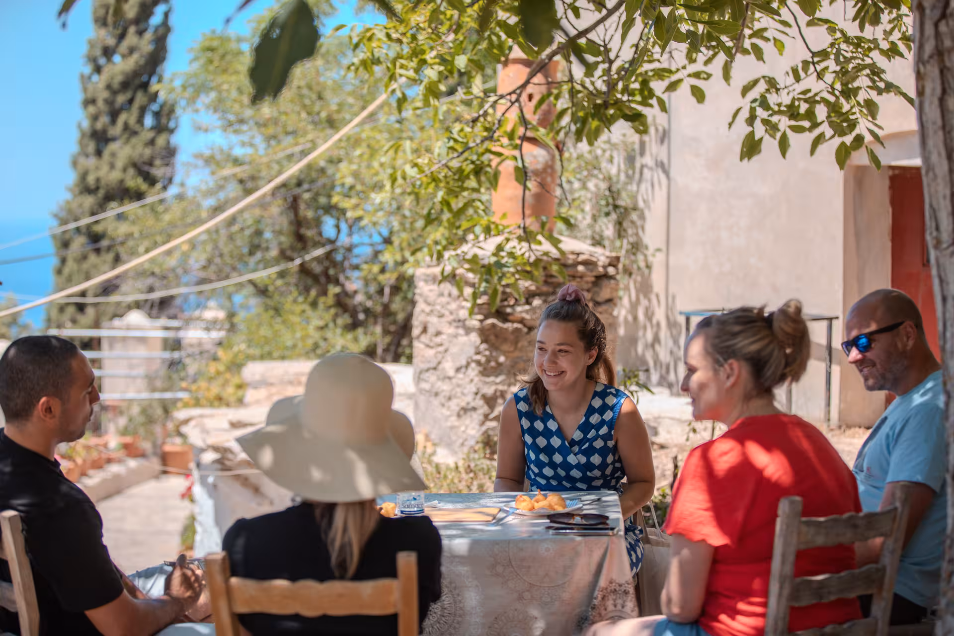 Small group enjoying a relaxed Ikarian lunch under trees with sea views on the Ikaria Longevity forest Pilates and winery tour