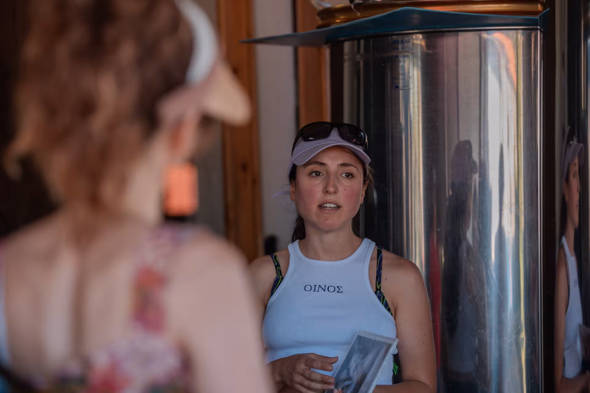 Local guide explaining wine production beside stainless steel vats during Ikaria Longevity family winery tour in Greece