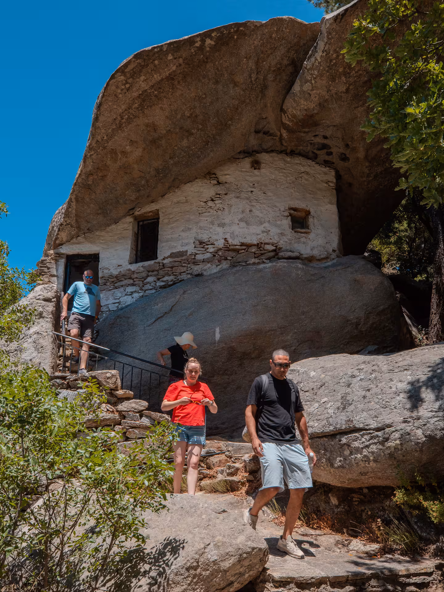 Small group explores a historic cliffside monastery carved into rock on Ikaria island, discovering local heritage and sacred sites