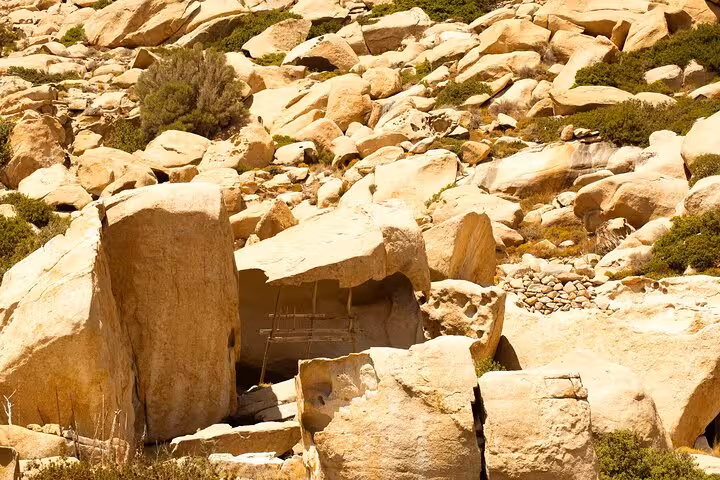 Sunlit boulder field and ancient stone shelters on Ikaria’s west side, showcasing wild landscapes and nature trails