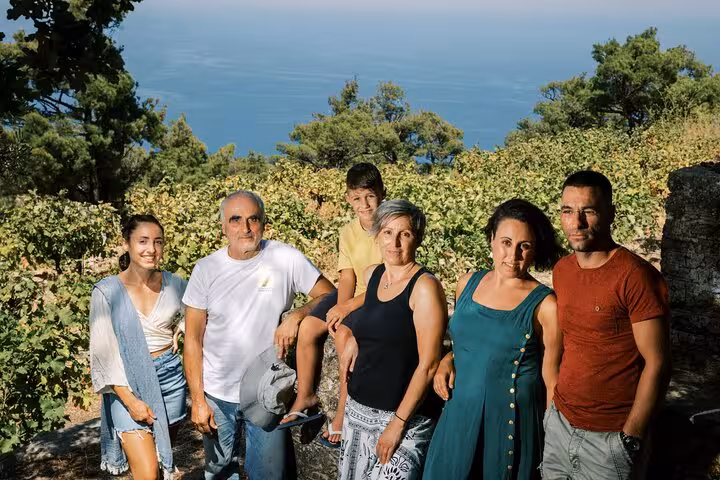 Local Ikarian winemaking family posing in their vineyard overlooking the Aegean Sea on a small-group winery tour