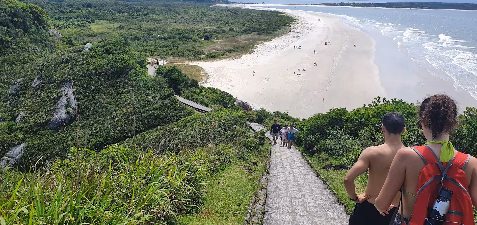 Tourists walking down a scenic path to a pristine beach on Ilha do Mel during a private tour experience.