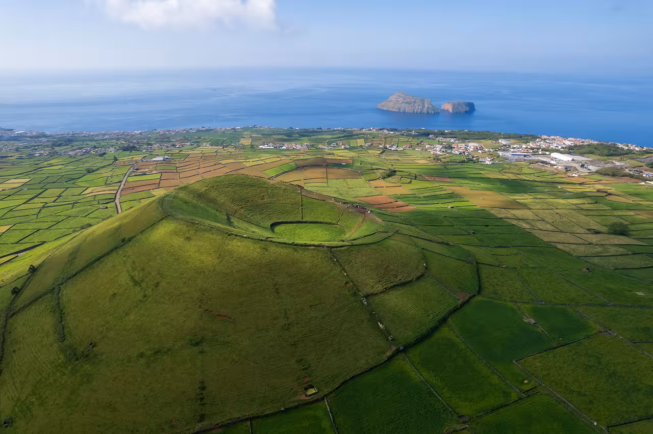 Aerial view of Terceira Island green fields with Ilhéus das Cabras offshore, Azores, during 2-hour tour