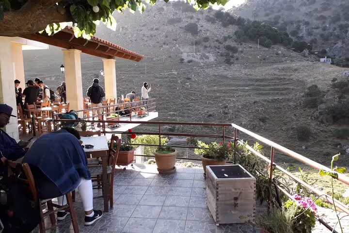 Tourists relax on a terrace with panoramic views of Imbros Gorge, ideal for a break during a private hiking tour.