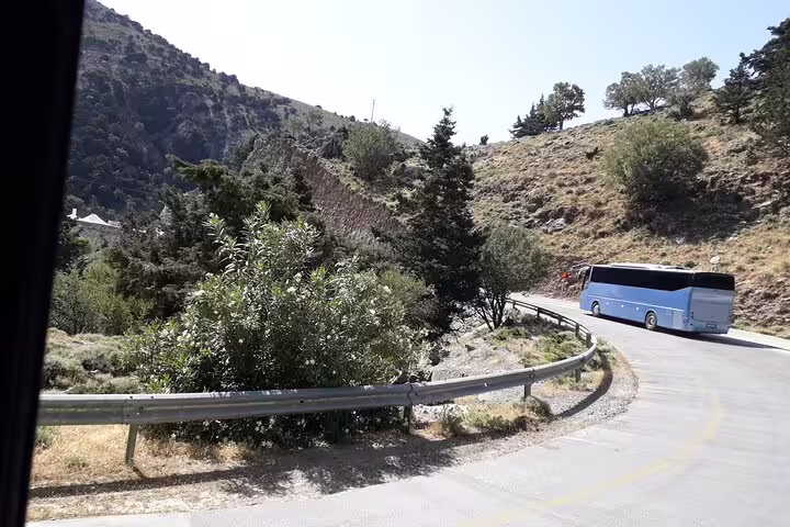Tour bus navigating winding roads through rugged terrain en route to Imbros Gorge private hiking adventure.