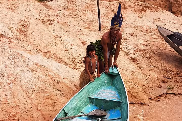 Indigenous family by canoe on sandy Amazon riverbank, cultural stop on 4-day Manaus boat tour