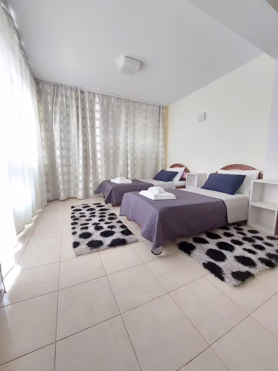 Spacious twin bedroom with elegant curtains and chic decor at Infinity Night Villa, perfect for relaxation.