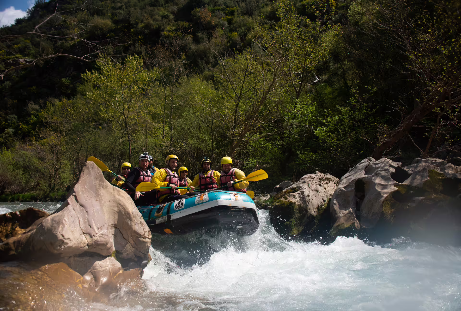 Inflatable raft tackling whitewater rapids between boulders on the Lousios and Alfeios rafting tour, Greece