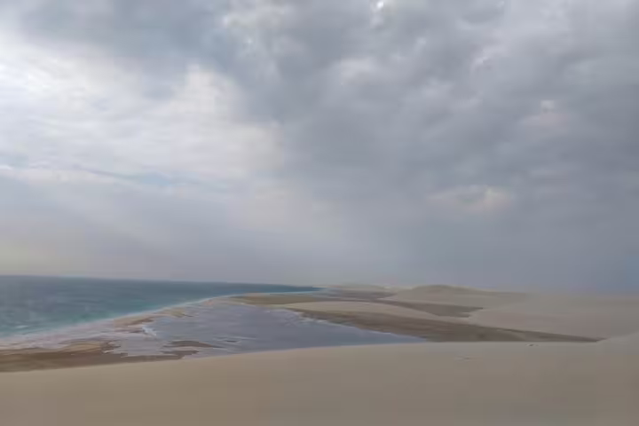 Expansive view of the inland sea meeting sandy dunes under a dramatic sky on a unique safari journey.