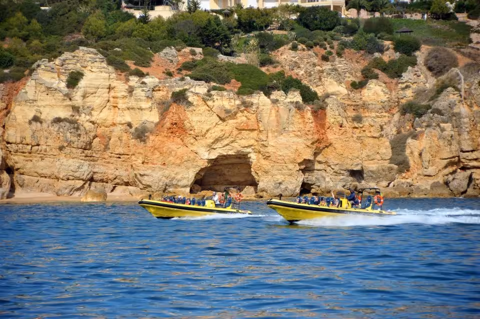 Two yellow speedboats with tourists exploring scenic coastal caves on the Insonia Caves & Dolphin Watching tour.
