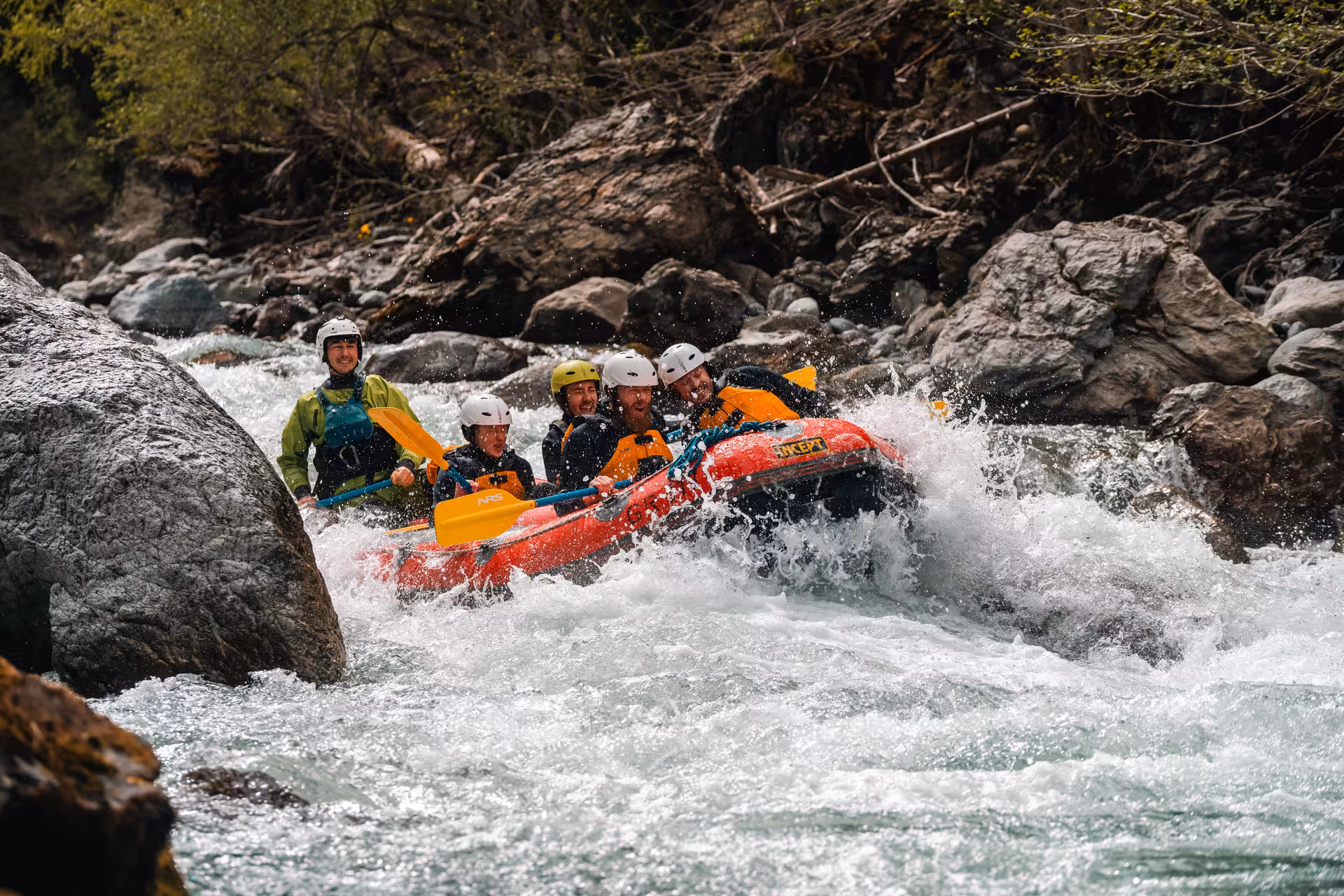 Adventure seekers navigate the thrilling rapids of Interlaken on a whitewater rafting tour, paddling through rocky waters.