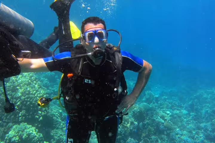 New diver practicing buoyancy beside coral garden on an intro diving and snorkeling day trip in tropical waters