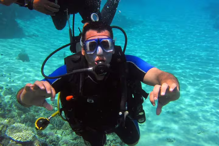 New diver practicing buoyancy over shallow reef during intro scuba diving and snorkeling day trip