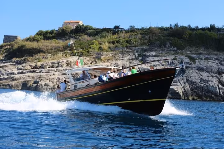 Tour boat cruising along the rocky coast of Ischia Island, offering a thrilling experience on the full-day boat tour.
