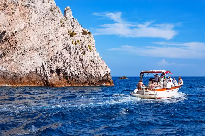 Small group enjoying a boat tour near scenic rocky cliffs between Ischia and Procida from Sorrento.