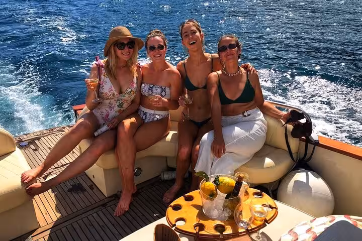 Group of friends enjoying a sunny boat tour around Ischia, sipping drinks and soaking up the Mediterranean sun.