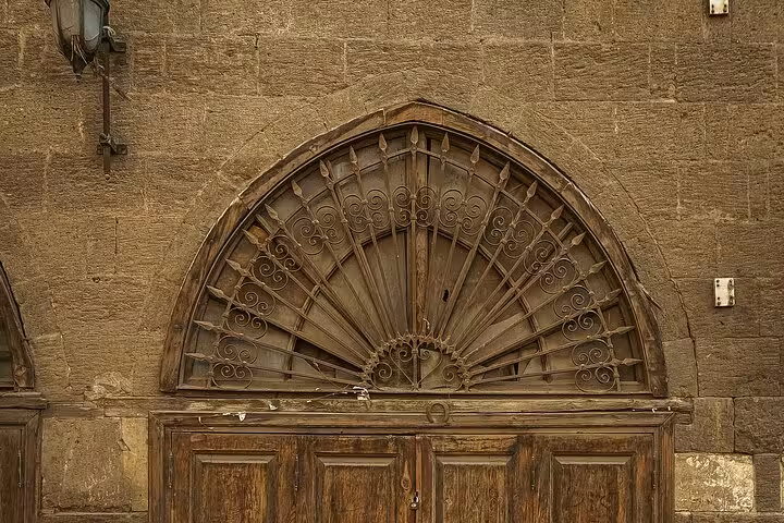 Historic arched doorway with wrought-iron fanlight in Islamic Cairo, Medieval Cairo old city heritage tour stop